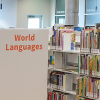 The endcap of a Library bookshelf reading "World Languages," behind which is another shelf with its books visible