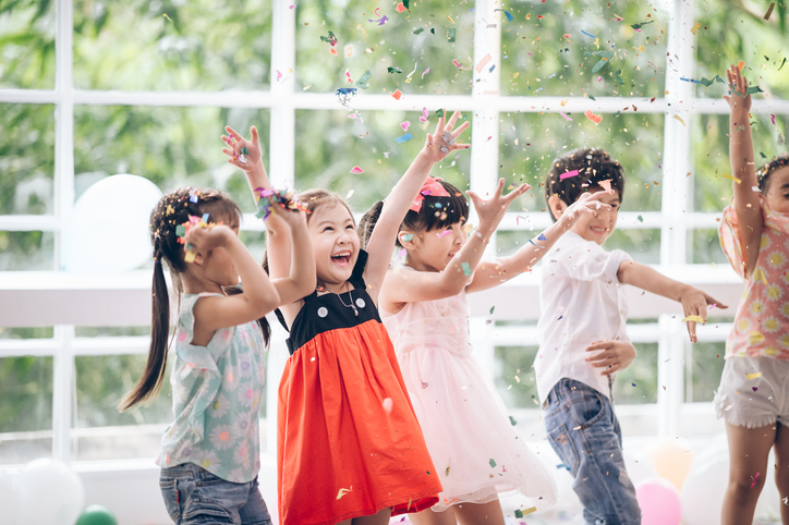 Photo of children playing and throwing confetti in the air.