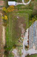 Aerial view of rural lot partially grassy and partially lined with hay bales.