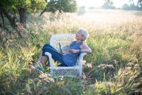 Author Anne-Marie Oomen reclining in a white wicker chair in a field