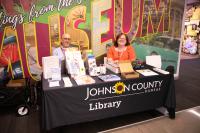 two librarians sit behind a table full of informational materials