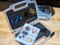 Plastic case with foam insert containing a soldering iron and other tools