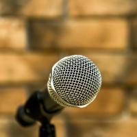 A microphone on a stand in front of a brick wall
