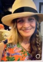 Annie Newcomer woman smiling with long hair braided on one side wearing a hat with a black band