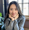 Ruth Wu young woman smiling with chin in hands long dark hair looking directly into the camera